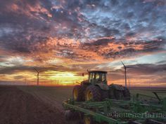 a tractor in the middle of a field at sunset