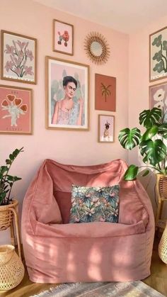 a living room with pink walls and pictures on the wall, plants in vases