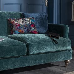 a blue couch with two pillows on top of it in front of a wall and floor