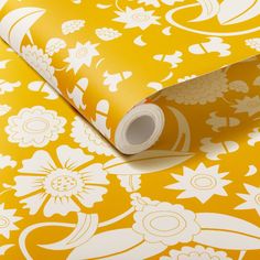 a yellow and white wallpaper with flowers on it's side, next to a roll of tape