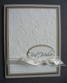 a white card with a ribbon on the bottom and an embellishment that says best wishes