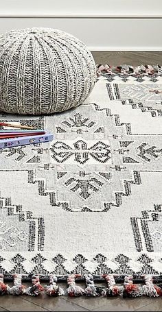 a white and black rug sitting on top of a wooden floor next to a pillow