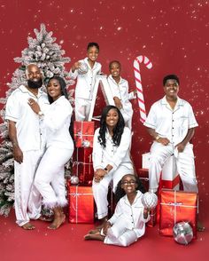 a group of people standing next to each other with presents in front of a christmas tree