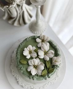 there is a cake with white flowers on the top and green icing around it