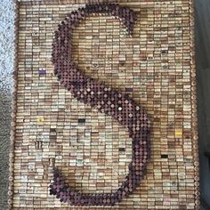 a wooden table topped with lots of wine corks and a letter s on it