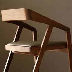 a wooden chair with a leather seat and back rest in front of a beige wall