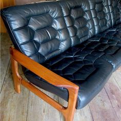 a black leather couch sitting on top of a wooden floor