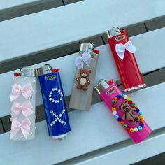 four different colored lighters with bows on them sitting on a white bench next to each other