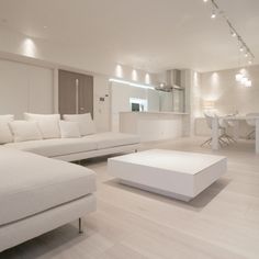 a living room filled with white furniture and lights on the ceiling above it's windows