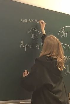 a woman writing on a blackboard with chalk