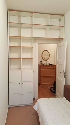 an empty bedroom with a bed, dresser and bookcases in the closet area