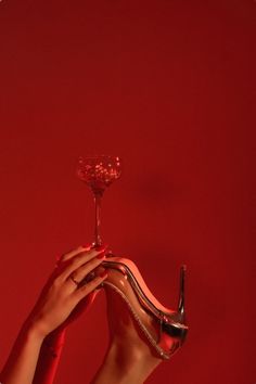 a woman's hand holding a wine glass in front of a red background,