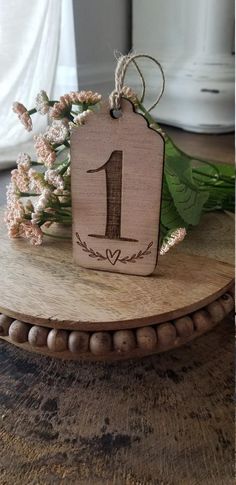 a wooden sign with the number one on it sitting on a table next to flowers