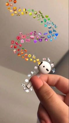 a hand holding a tiny toy with many different objects coming out of it's mouth