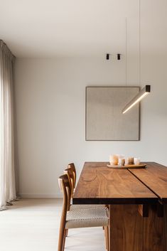 a wooden table with two candles on it in front of a large painting hanging from the ceiling