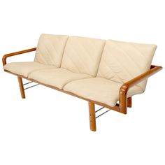 a white leather couch with wooden frame and armrests