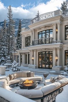 a large white house with a fire pit in the front yard and snow on the ground