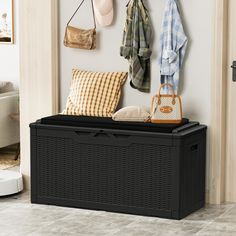 a black storage box sitting on top of a tiled floor next to a coat rack