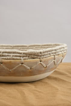 a bowl sitting on top of a wooden table next to a brown cloth covered wall