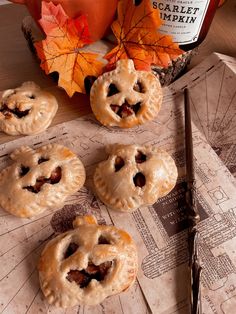 four small pies on a table next to a candle and an orange pumpkin jar