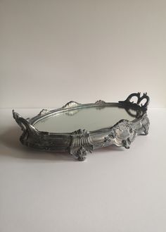 an ornate silver tray on a white table with a mirror in the shape of a heart