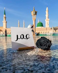 a piece of paper with the word yo written on it next to a flower in front of a mosque