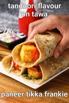 a person is grabbing food from a wrapper on a plate with the words paneer tika frankie