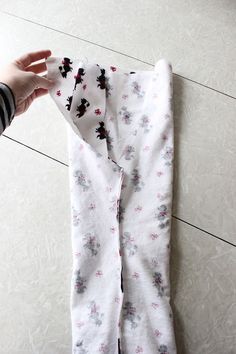 someone's hand is holding the bottom of a pair of leggings with flowers on them