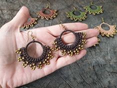 a hand is holding three pairs of beaded earrings