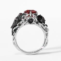 three stone ring with black and red stones on the sides, set in white gold