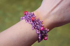 a woman's arm with a bracelet made out of beads and flowers on it