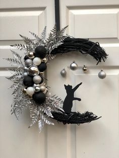 a black and white wreath with ornaments hanging from it's side on a door