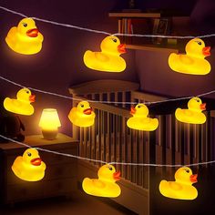 several rubber ducks are hanging on a string in the dark, with lights strung from them