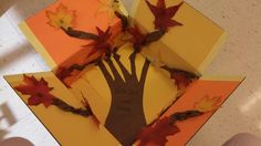 someone is holding their hand out to make a paper fall tree with leaves on it