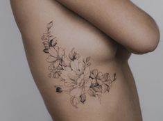 a woman's breast with flowers tattooed on the side by tattoo artist in black and white