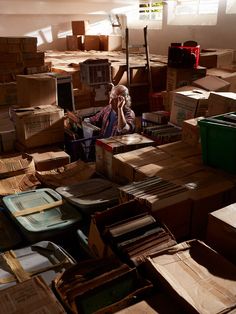 an old man sitting in a room full of boxes