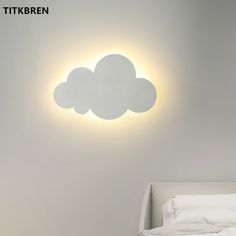 a white bed sitting under a bright light in a bedroom next to a wall mounted cloud