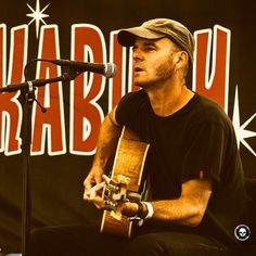 a man sitting in front of a microphone while holding a guitar