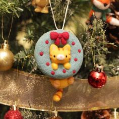 a christmas ornament with a cat on it hanging from a tree in front of ornaments