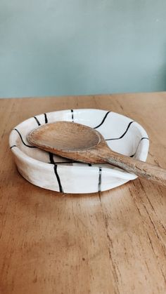 a wooden spoon sitting on top of a white and black plate next to a blue wall