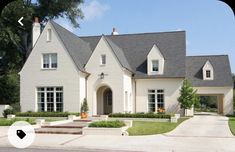 a large white house with lots of windows on the front and side of it's roof