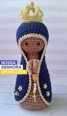 a crocheted doll wearing a blue and gold outfit with a crown on top