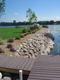 there is a dock that has rocks on it and grass in the backround