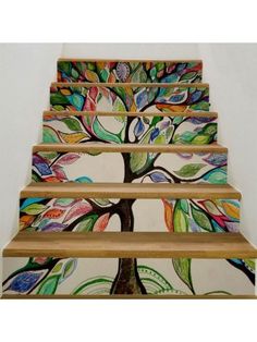 an artistic stair case painted with colorful leaves and tree design on the bottom, along with wooden handrails