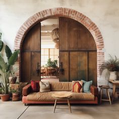 a living room filled with lots of furniture next to a brick wall and an arched doorway