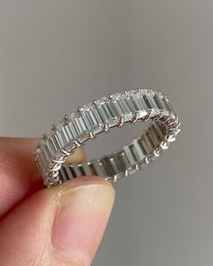 a person is holding a ring made out of white gold and baguettes set with diamonds