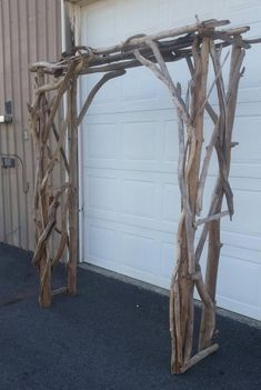 a wooden arch made out of branches in front of a garage