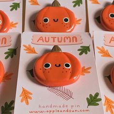 four orange pumpkin magnets with faces and leaves on them, sitting in front of each other