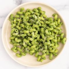 a white plate topped with green pasta covered in pesto