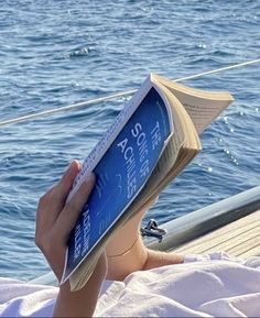 a person reading a book while sitting on a boat